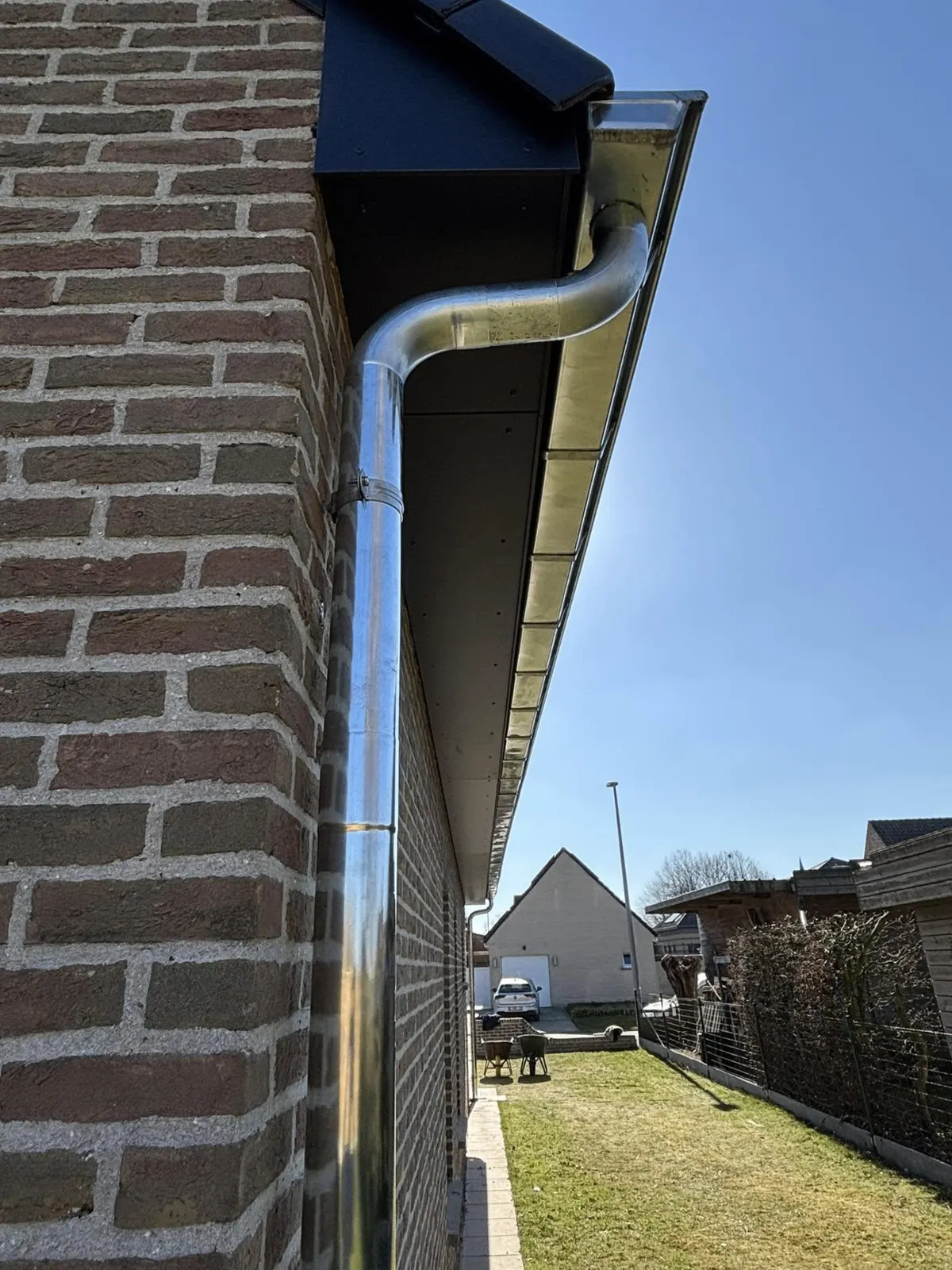 Zinken dakgoot langs een bakstenen woning